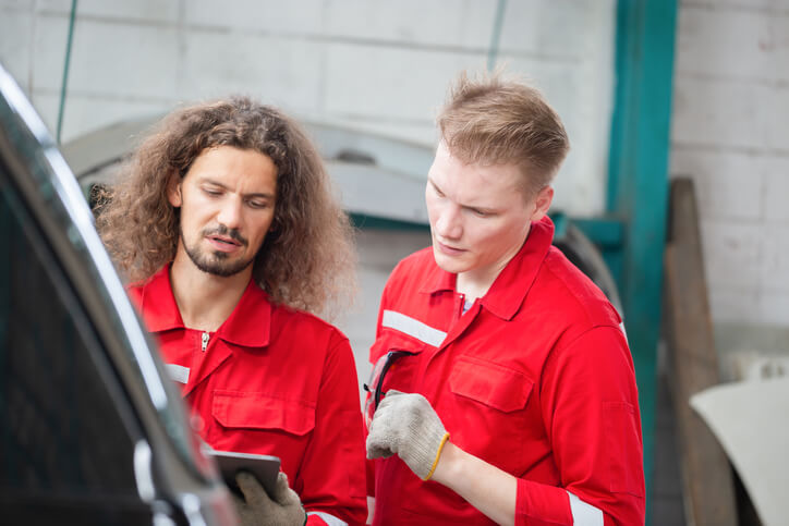 An automotive training student working on a vehicle with an ATC instructor
