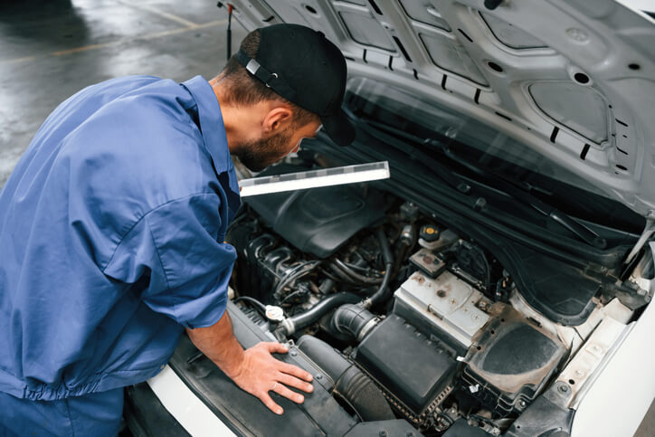 An auto mechanic inspecting a high-mileage vehicle in a repair shop