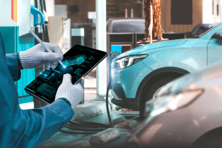 An auto mechanic repairing an electric vehicle using advanced diagnostic equipment