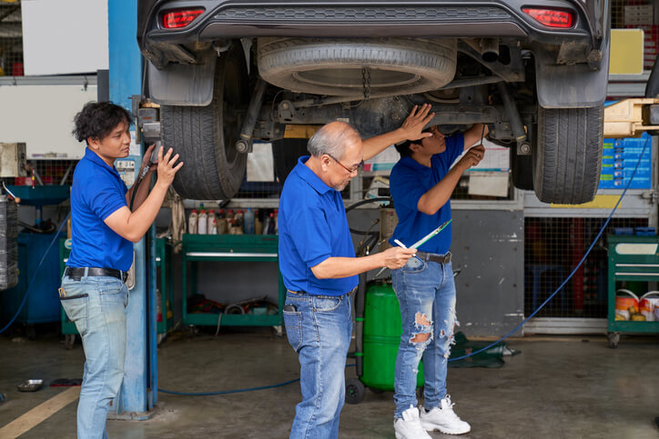 An auto mechanic training instructor showing students how to use a vehicle lift safely