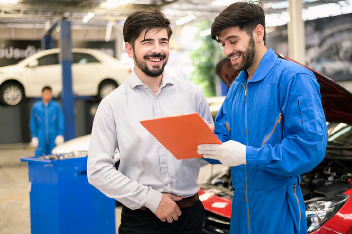 An auto mechanic reviewing a service checklist with a client