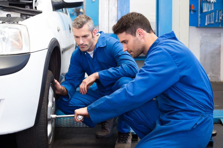 An Auto mechanic instructor supervising a tire change