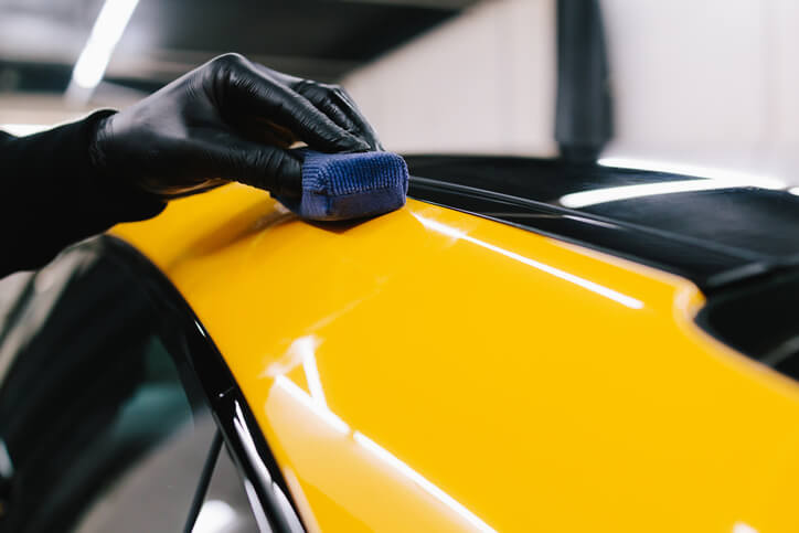 A professional applying ceramic coating to a car surface for long-lasting paint protection.