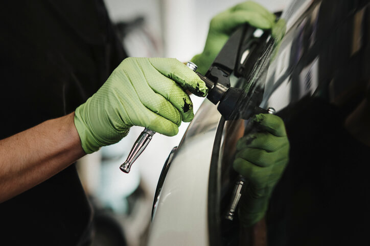Close-up of a technician’s hands working on a vehicle part.