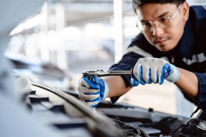 An auto mechanic training hands-on engine repair in garage