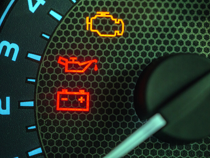 A close-up of dashboard warning lights used in auto mechanic training and vehicle diagnostics practice.