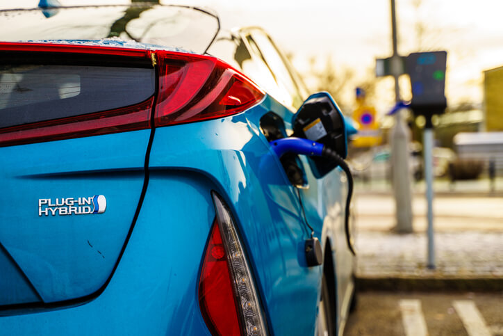 A hybrid technology training image of a plug-in hybrid car connected to a public charging station.