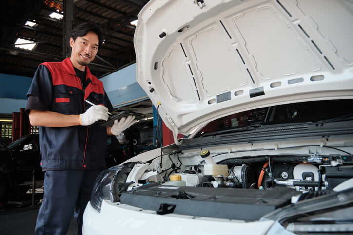 A hybrid and electrical mechanic training with a student diagnosing a car engine.