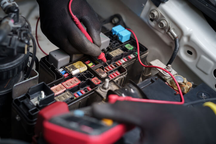 A close-up of a mechanic's hands testing a vehicle’s electrical system as explored during automotive training in Montreal.