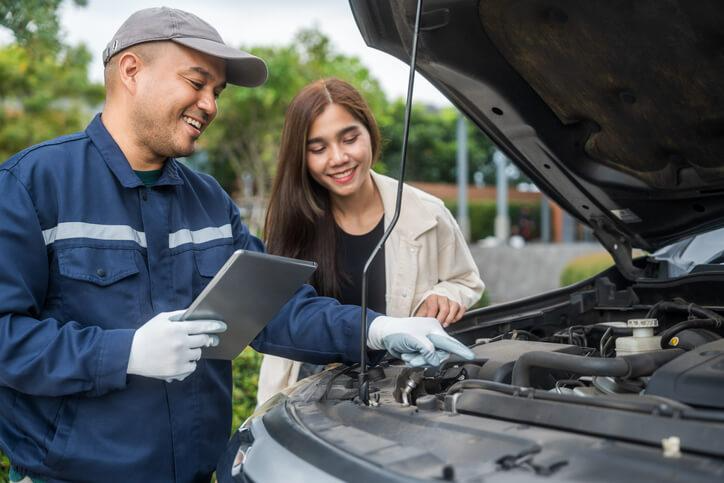 An automotive Service Technician training in Toronto: a mechanic explaining car repair to a customer under the hood