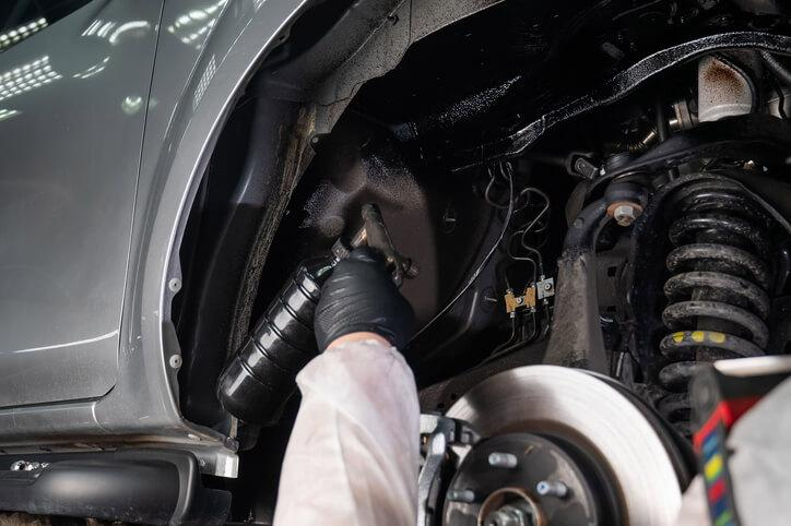 A mechanic inspecting drivetrain and suspension car components