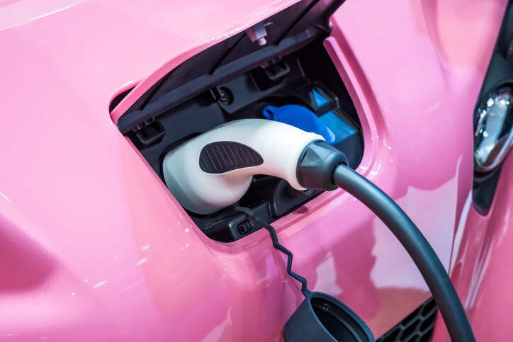 A hybrid technology training example of an electric vehicle mechanic plugging a charger into a car’s charging port.