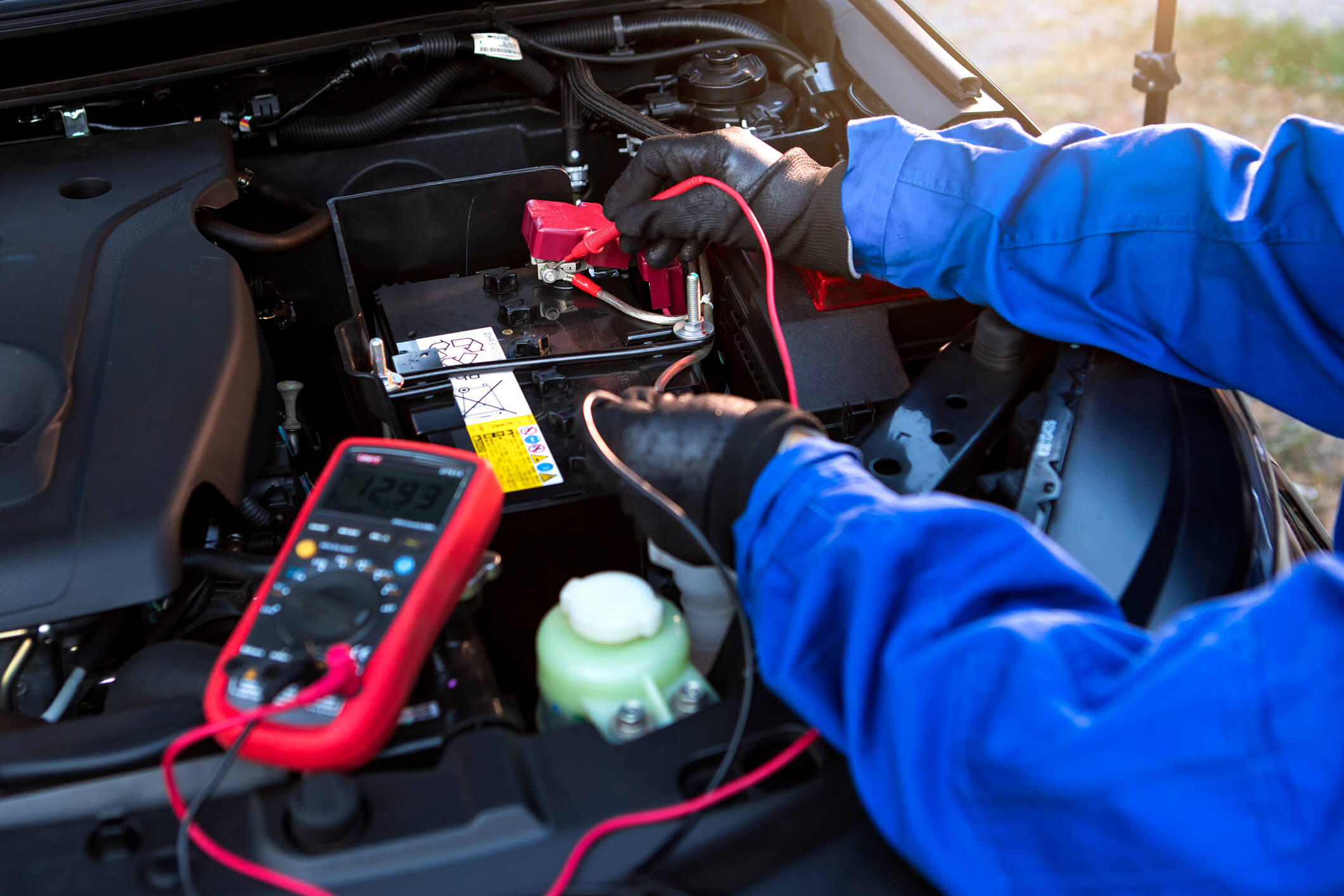 A student practices high-voltage safety during hybrid and electrical mechanic training using diagnostic tools.