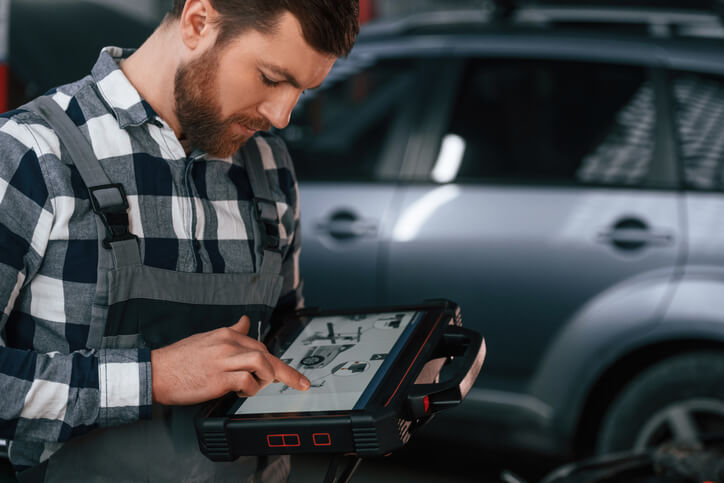 An auto mechanic using a scan tool to read ECU data