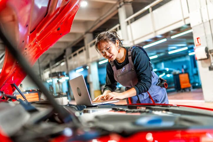 An auto mechanic school student diagnosing an electric vehicle battery using software.