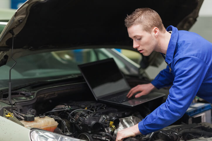 An auto mechanic student learning computer diagnostics on a modern car