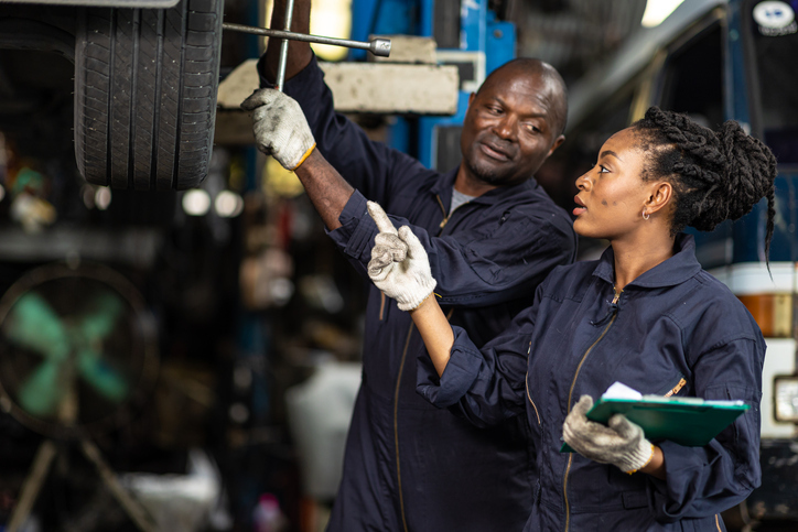 A close-up of a student checking engine components at an auto mechanic school workshop