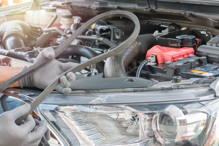 An automotive service technician program student inspecting engine belts in a training garage