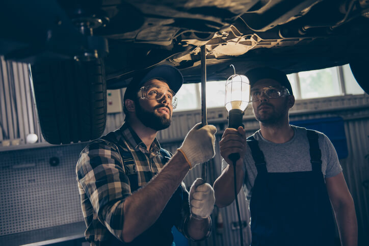 An electric vehicle mechanic is diagnosing a problem with a student during hands-on training.