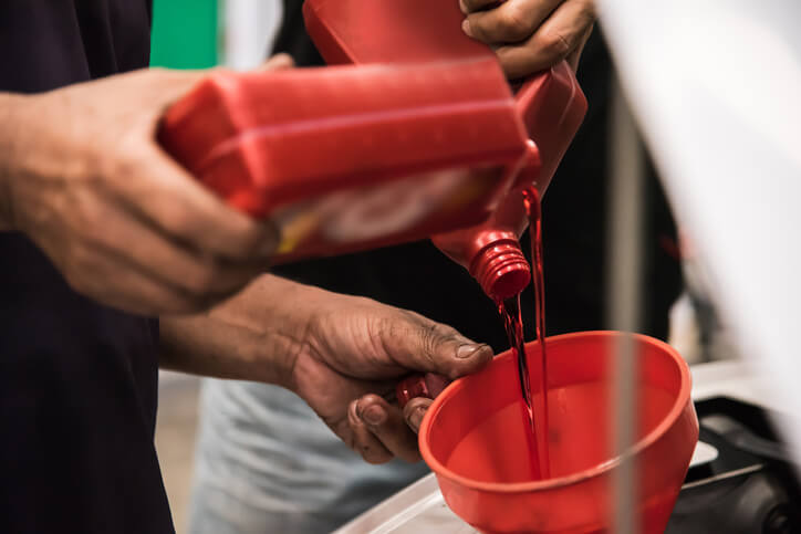 An instructor overseeing a student in the auto mechanic course during a scheduled oil change demo