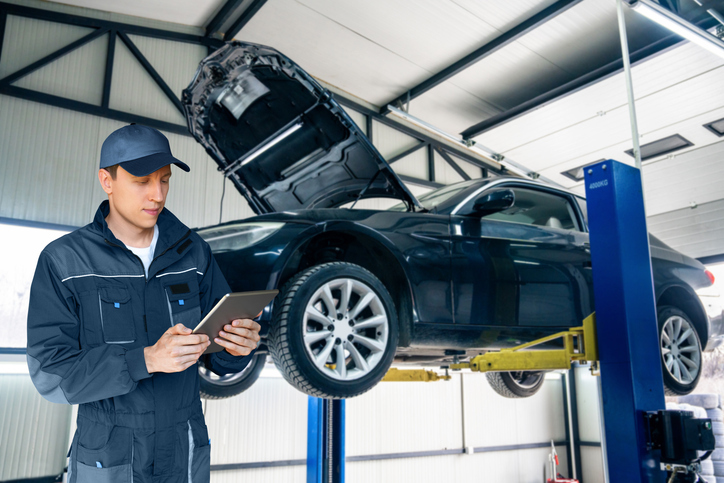 An instructor showing students how to identify fluid leaks during automotive training