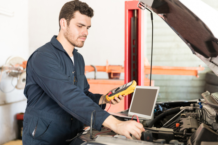 Auto mechanic student avoiding errors by checking diagnostics at auto mechanic school