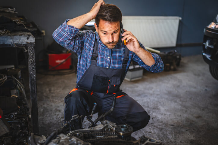 A student at an auto mechanic school in Surrey using a laptop to diagnose an electrical issue under the hood.