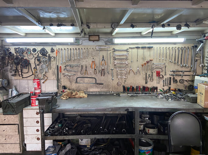 An auto mechanic school in Surrey, trainee organizing tools and maintaining a safe, clean workshop area