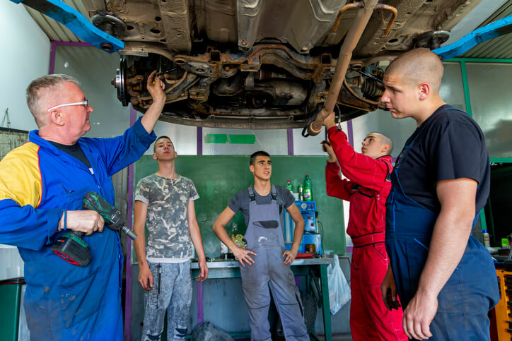 An instructor guiding adult learners through practical auto mechanic courses in Surrey