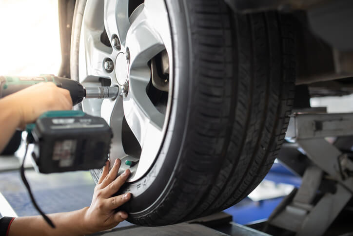 An auto mechanic training student checking wheel balance on a diagnostic machine