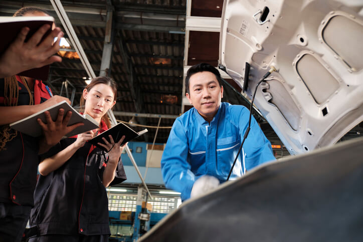 An instructor showing vacuum leak testing to an automotive training class