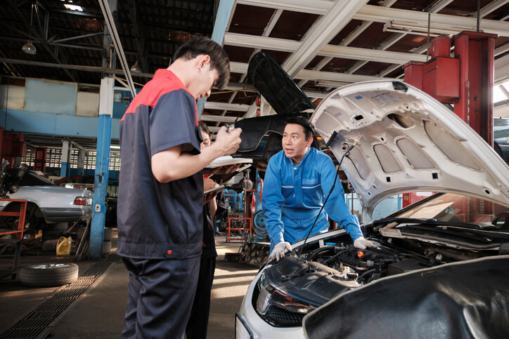An auto mechanic school: A student discussing a repair job with an instructor in the workshop.