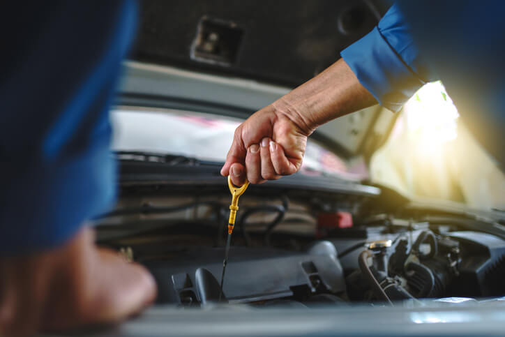 A mechanic checking engine oil during hands-on training at an auto mechanic school