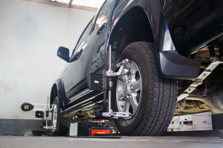 A technician using wheel-alignment equipment as part of auto mechanic training to diagnose handling and pull concerns.