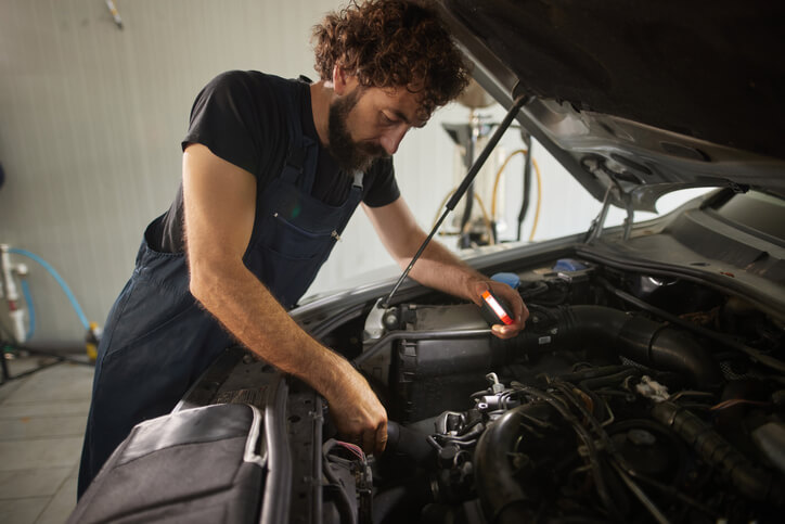 An auto mechanic training student diagnosing a rough idle on a vehicle
