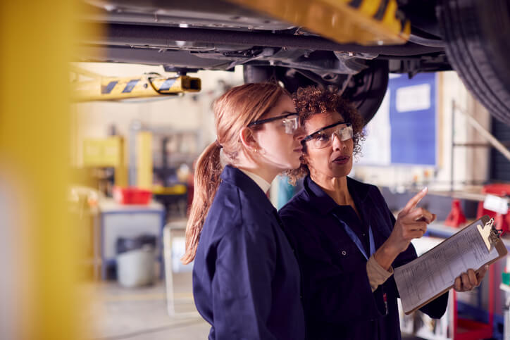 An instructor mentoring a student in an auto mechanic school workshop during automotive training