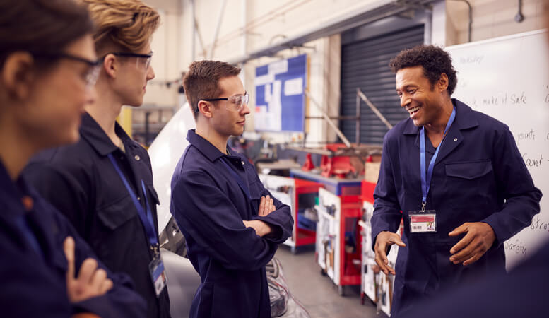 An instructor teaching auto mechanic apprentices in a classroom setting as part of an automotive service technician program.