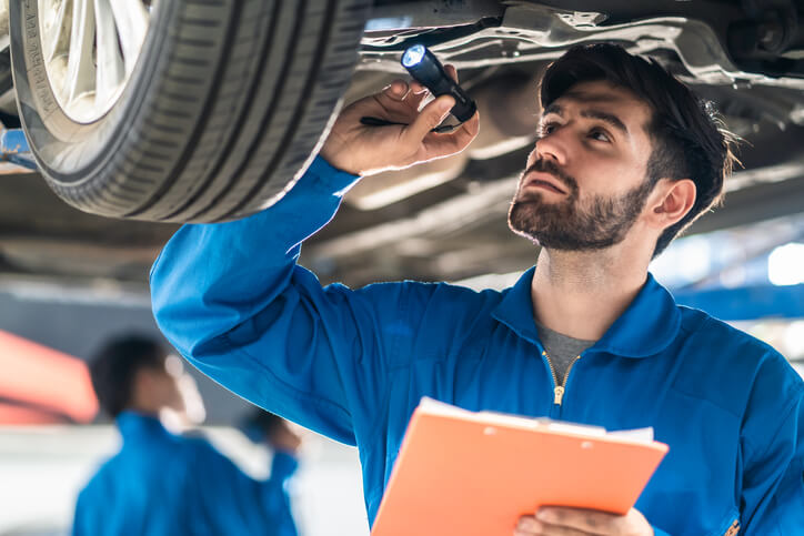 Auto mechanic student inspecting a vehicle on a lift during hands-on training.