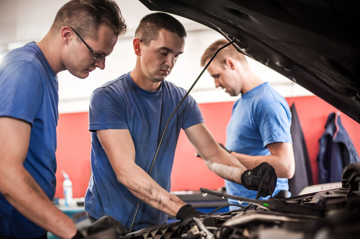 A student from an auto mechanic school in Surrey learning hands-on skills in a training shop environment.