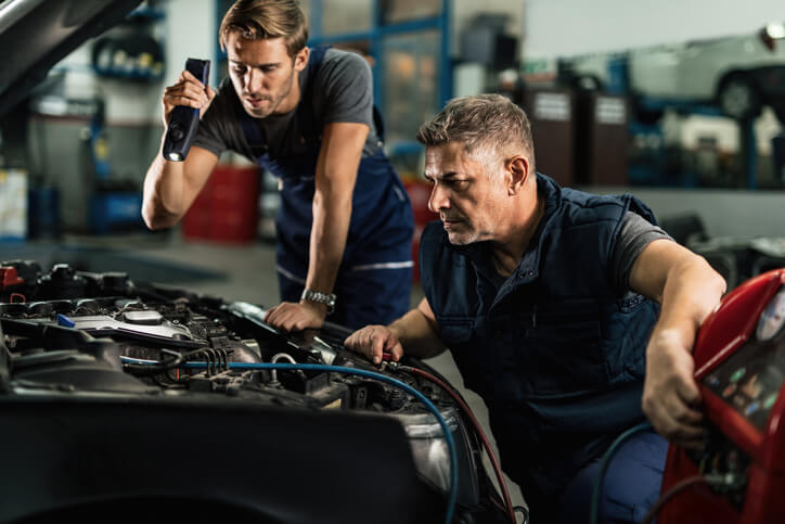 A pair of automotive service technician program graduates testing vehicle systems during a diagnostic process, relying on structured methods to resolve unclear problems