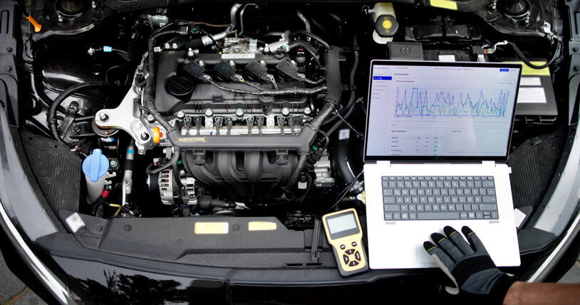A student in an automotive school garage using a diagnostic scanner during hands-on auto mechanic training.