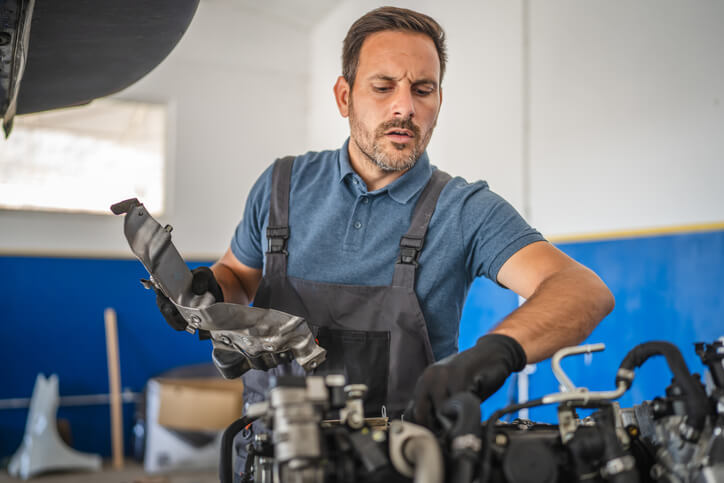 An automotive service technician program graduate working in a busy automotive repair shop
