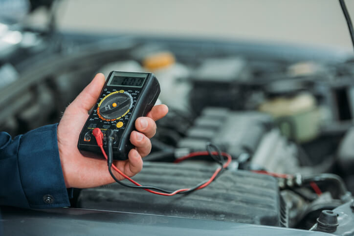 A student in an automotive school garage using a diagnostic scanner during hands-on auto mechanic training.