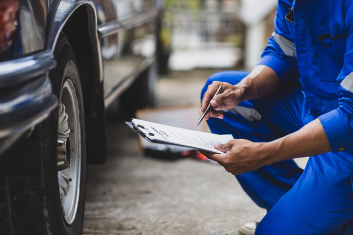 An auto mechanic student reviewing notes after receiving feedback during hands-on training.