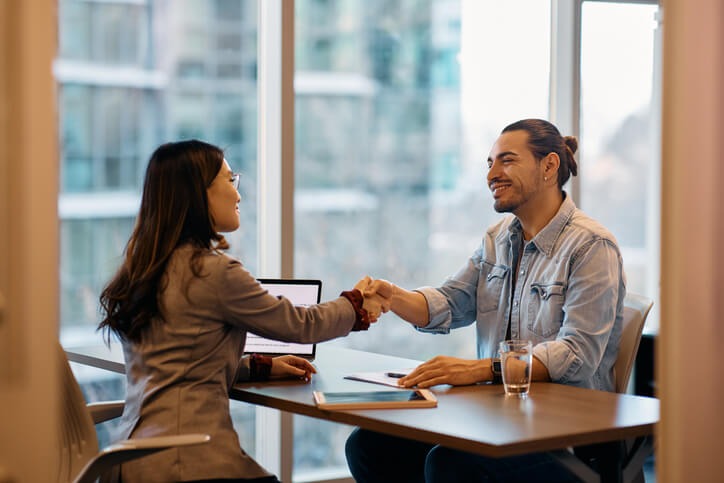Auto mechanic job candidate shaking hands with an interviewer after a successful first interview.
