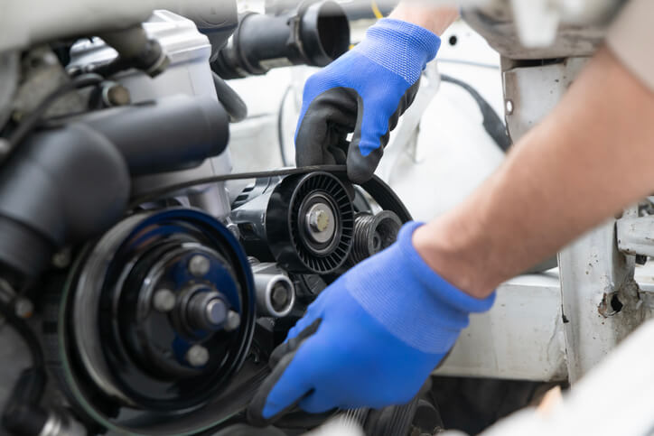 A technician performing crank/cam correlation testing with an automotive oscilloscope connected to engine sensors.