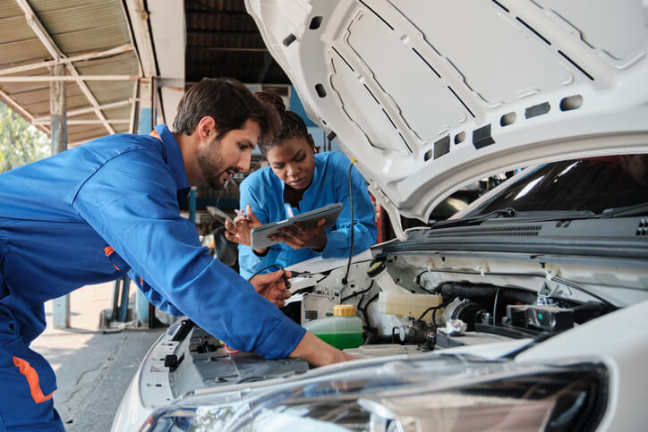 A Team of mechanics is inspecting an electric vehicle in a service garage.