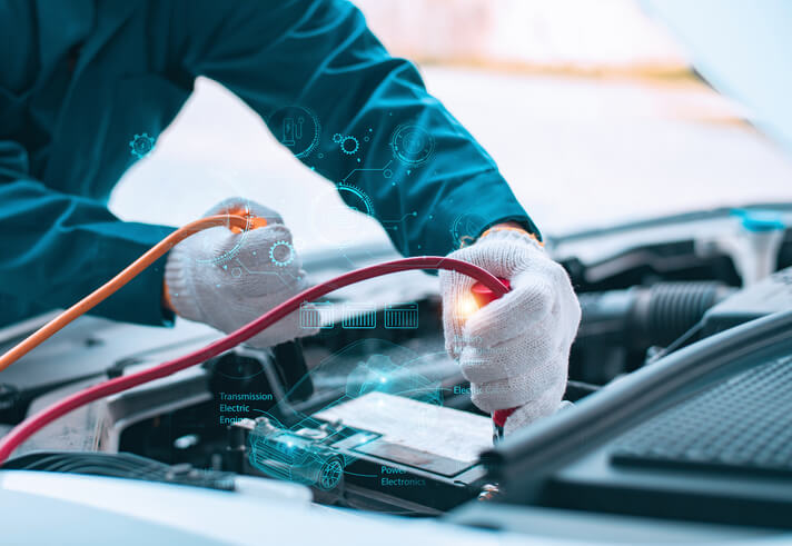 An EV mechanic in gloves is inspecting an electric car battery system.