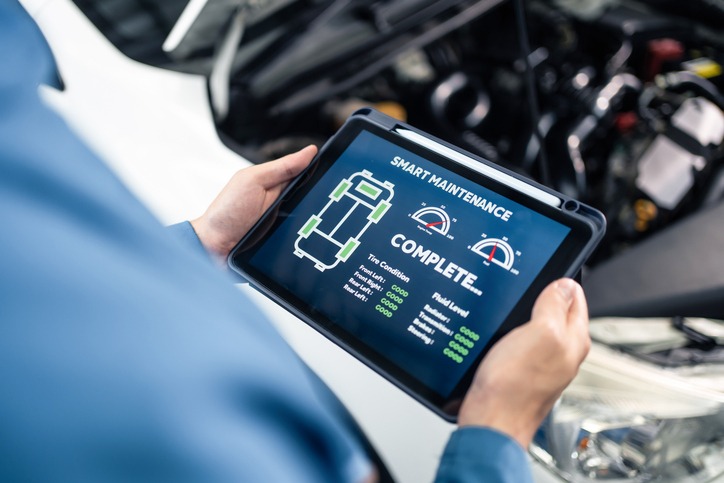 Technician using remote car diagnostics software on a tablet.