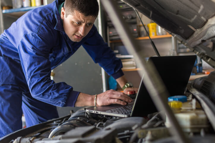 A student at an automotive school practicing computerized vehicle diagnostics in a workshop